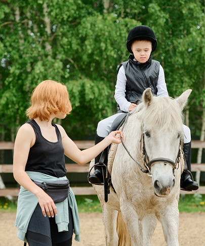 Instructor leading young child on white pony during riding lesson at Woodbine Farms Michigan